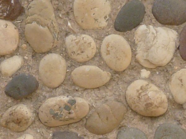 Smooth and round pebbles firmly set in light brown concrete.